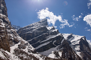 Snow covered mountains rise dramatically against a vibrant blue sky in the Annapurna region