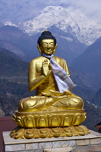A serene golden Buddha statue is positioned prominently against the backdrop of majestic Annapurna peaks