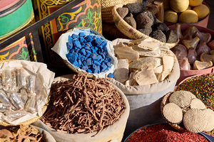 Colorful spices herbs and natural materials fill sacks and baskets on display at an outdoor market
