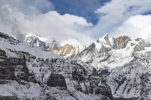 Mountains covered with snow and partial cloud cover under  blue sky in Annapurna Sanctuary Nepal