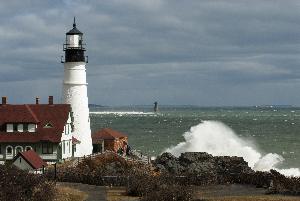 Waves Crash By Portland Head Lighthouse as Sun Breaks Through Clouds