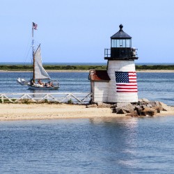 Sailboat Passes Brant Point Lighthouse on Nantucket Harbor in Massachusetts