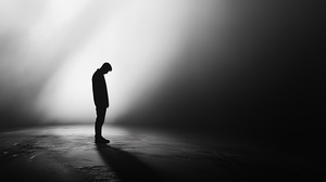 Silhouette of a person standing in solitude against a dark backdrop with dramatic lighting effects