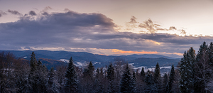Wide panorama of winter mountains and forest at dusk
