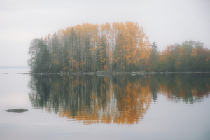 A serene autumn island scene with colorful trees reflected in tranquil waters.