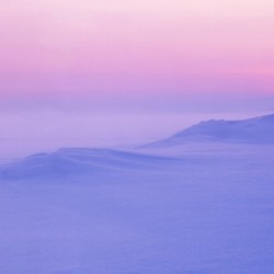 Arctic sunset illuminates the snow-covered landscape in soft pastel hues.