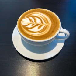 White cap of coffee latte on a black desk surface