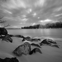 Black and white sunrays over the frozen lake