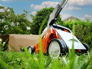 New unboxed lawnmower in the garden with tall trees in background