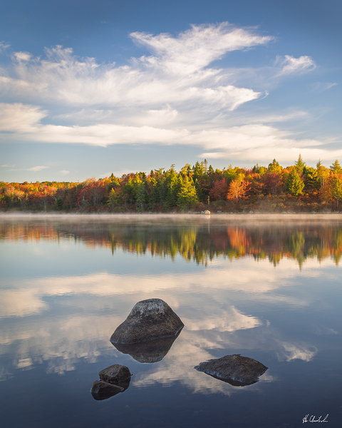 Wispy clouds over a calm lake in autumn by Hugh Chisholm Photography
