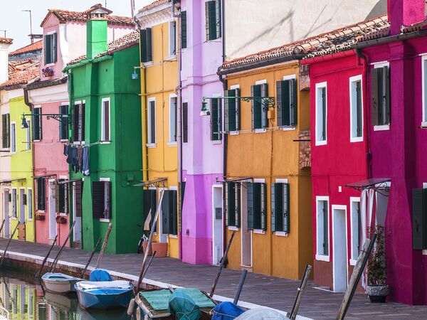 Multi Coloured houses next to a canal Burano Italy by Assaf Frank