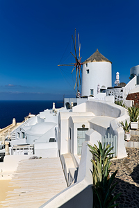 Santorinis iconic white architecture and windmill by the sea.