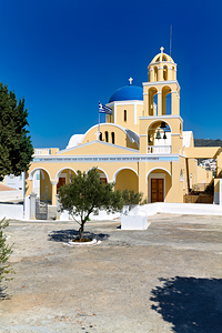 Beautiful Greek church with blue dome and bell tower.