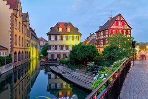Timber framed houses and visitors in Colmar canals at dusk