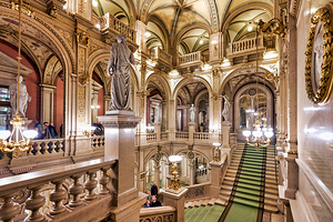 Luxurious opera house interior with grand staircase and statues.