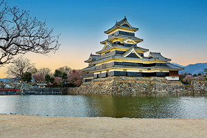 Matsumoto Castle standing by water during sunset in Japan