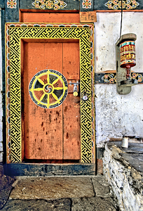 Colorful Bhutanese door with Dharma wheel and prayer wheel.