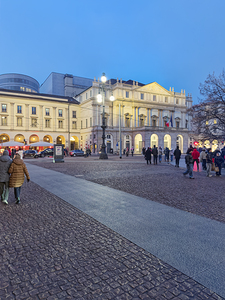 Milan. Italy. La Scala opera house piazza at dusk with people wa