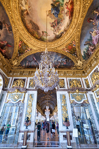 Visitors explore the grand hall of the Palace of Versailles in F