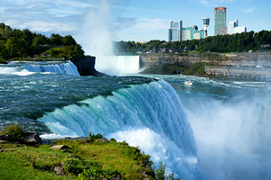 Niagara Falls with city skyline and boat.