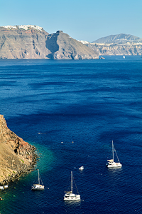 Scenic Santorini caldera with boats and white villages.
