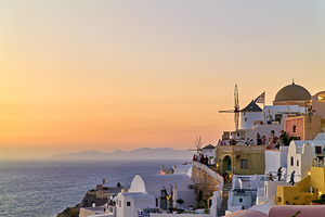 Sunset over Santorini village windmills and Aegean Sea.