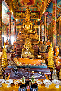 Golden Buddha statues and offerings in an ornate temple.