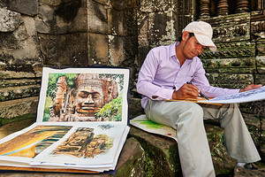 Artist drawing ancient temple carvings outdoors.