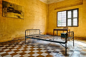 Tuol Sleng Genocide Museum cell with bed and victim photo.