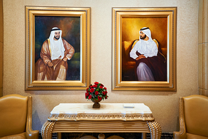 Formal portraits of UAE leaders in an opulent room.