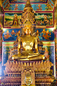 Ornate golden Buddha statue surrounded by colorful temple murals