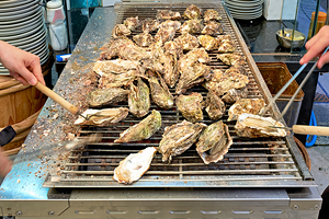 Grilling oysters in restaurant on Miyajima island in Hiroshima