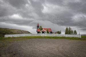 Small church standing on a hill under a dramatic sky