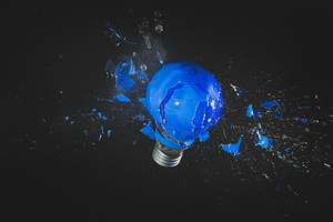 blue light bulb exploding on black. 