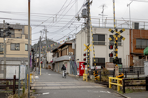 Man riding bicycle approaching japanese railroad crossing 
