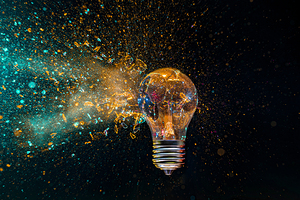 Bright idea exploding lightbulb with colorful powder on black ba