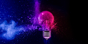 Pink light bulb exploding in colorful powder on black background