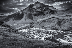 River flowing through green valley with mountain in background