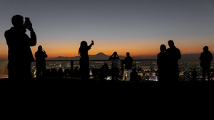 Tourists taking pictures of mount fuji at sunset from tokyo roof