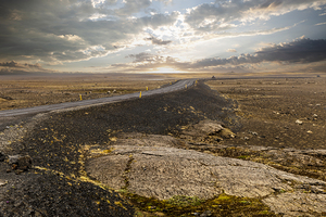 winding asphalt road crossing a vast otherworldly volcanic terr