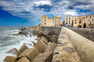 Sea waves crashing against the fortified walls of cefalu touris