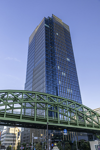 Modern glass office tower rising above green train bridge