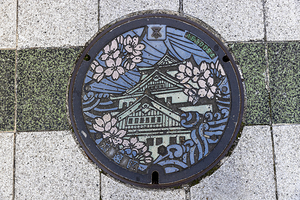 Detailed manhole cover depicting japanese castle with cherry blo