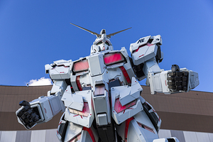 Giant gundam robot standing tall against blue sky in odaiba