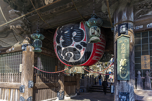 Tourists walking under a large paper lantern hanging at the entr