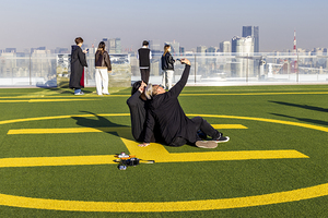 Tourists taking pictures on rooftop with tokyo skyline