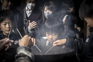 Asian family praying with incense sticks at temple