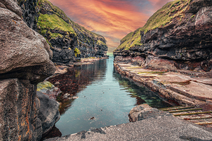 Calm water reflecting dramatic sky in gjogv faroe islands