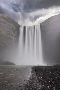 Lone tourist admiring majestic waterfall cascading from mountain