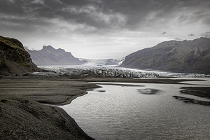 River flowing from melting glacier under cloudy sky